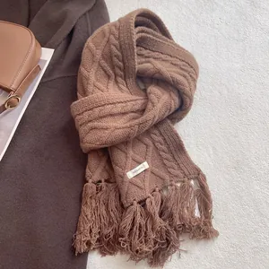 Macro detail of caramel 100% wool scarf showing cable knit texture and soft fringe