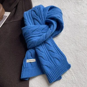 Détail de la maille torsadée bleue et étiquette 100% laine sur l'écharpe d'hiver