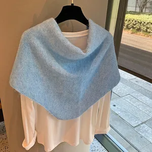 Detail of light blue knitted shawl wrap with soft mohair texture over white top
