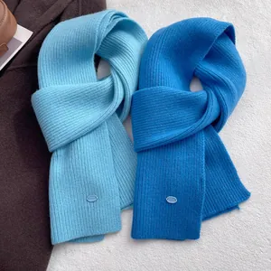 Detailed view of sky blue and royal blue wool scarves with ribbed texture and oval labels