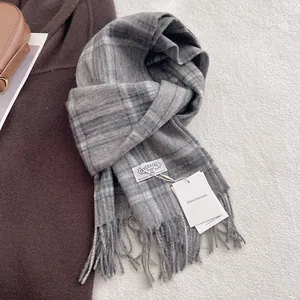 Detailed view of grey plaid 100% wool scarf with soft fringe texture and brand tags