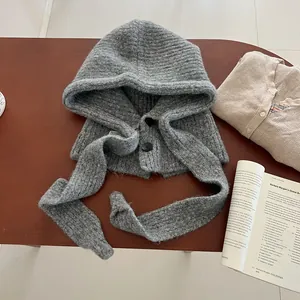 Detailed close-up of grey chunky knit balaclava hood with black button detail on wood table