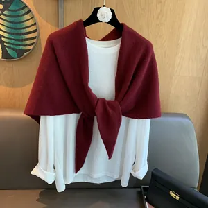 Detail of a deep red wool knit shawl knotted over a white long-sleeved shirt