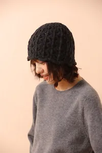 Detail of black wool crochet beanie featuring hollow diamond knit and wavy scalloped edge