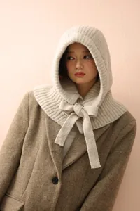 Détail d'une cagoule en tricot de laine avec nœud décoratif en teinte beige avoine