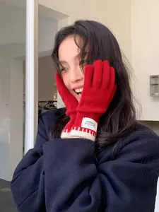 Detailed close-up of red knitted gloves with stitched fabric label and color-contrast edges
