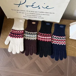 Detailansicht von vier Fair-Isle-Strickhandschuhen in verschiedenen Farben auf Holz