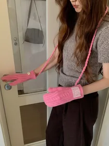 Detail showing pink cable knit mittens with long neck strap and white woven label