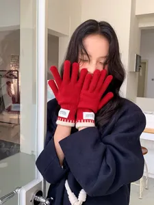 Detail of red knit gloves with white ribbed cuffs and Silent Wind woven label branding