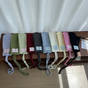 Detailed view of ten colorful knitted mittens with hanging neck cords and cable patterns