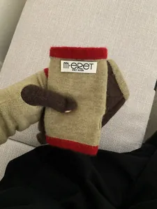 Close-up of knit fingerless gloves with khaki and red color-block and M·ERET woven label