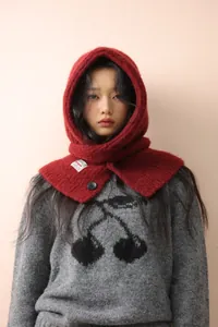 Close-up of a red knit balaclava hat with plush texture and black button detail