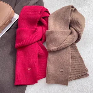 Detail of rose red and brown rib-knit wool scarves with premium metallic logo patches