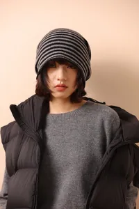 Dettaglio del berretto a maglia a righe con maglione grigio e gilet imbottito