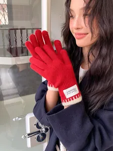 Close-up of red knit gloves with contrast white ribbing and finger slit for phone use