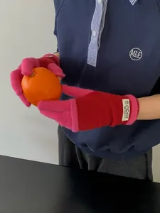 Detail of pink and orange knitted touch screen gloves with minimalist brand tag and soft texture