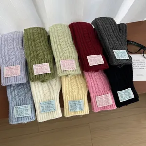 Flat lay of colorful cable knit fingerless gloves with bear labels on wooden surface