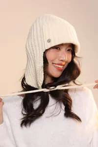 Dettaglio del cappello in maglia spessa con paraorecchie, trama a coste e logo