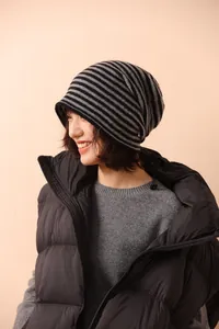 Dettaglio del berretto in maglia a righe nere e grigie su una modella per l'inverno