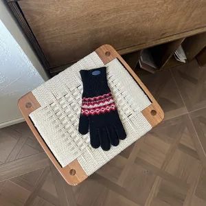 Detailaufnahme von Fair Isle Strickhandschuhen mit geometrischen Mustern auf weißem Grund