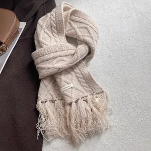 Detail of 100% wool cable-knit scarf with long fringe and high-quality material label