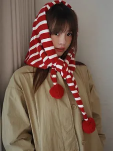 Detail of red and white striped knit hooded scarf with cute soft plush pom-pom charms