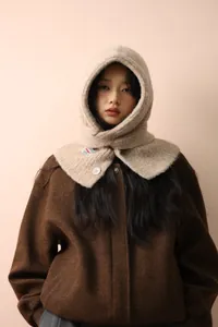Close-up of beige knitted balaclava hood with white button detail and brand label