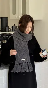 Detail of 100% wool cable knit scarf with thick tassels in a charcoal grey finish