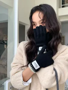 Detail of black knit gloves featuring striped wrists and a Silent Wind woven label