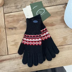 Details der Strickhandschuhe mit Fair-Isle-Muster und Touchscreen-Funktion auf Holz