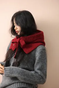 Détail de la maille épaisse et du nœud rouge de cette écharpe cagoule en laine