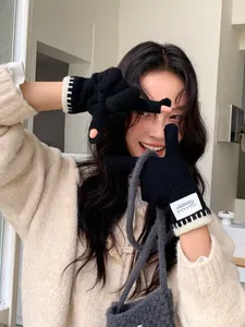 Close-up of black fingerless knit gloves featuring keyboard pattern cuffs and woven label