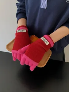 Detail of red and pink knit gloves with touchscreen fingers and m-ERET brand tag