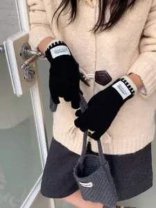 Close-up of black knitted gloves featuring a white Silent Wind woven label and ribbed cuffs