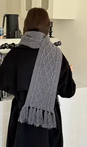 Detailed view of cable knit pattern and tassel fringe on a thick 100% wool gray scarf