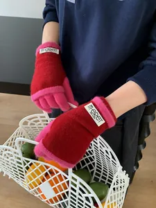 Detail of red and pink contrast knit gloves with tactile wrist cuff and woven label