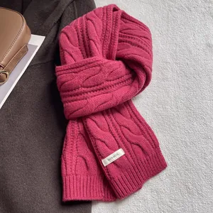 Détail macro de l'écharpe fuchsia 100% laine montrant la maille torsadée et l'étiquette
