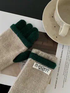 Close-up of beige and dark green knit gloves with touch screen design and brand label