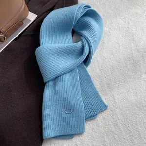Nahaufnahme hellblauer Strickschal aus 100% Wolle mit Rippenmuster und Logo-Aufnäher