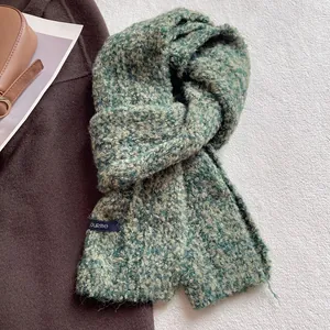 Dettaglio della sciarpa in lana boucle verde petrolio con trama tessuta e etichetta in tessuto
