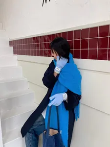 Detail view of cozy light blue knitted gloves and bright blue fleece scarf on a model