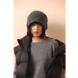 Berretto in maglia a righe nere da donna con maglione grigio e gilet imbottito nero