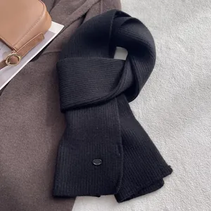 Detail eines schwarzen Strickschals aus Wolle mit Streifen und Metallschließe