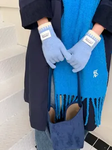 Detail of light blue knitted gloves featuring wavy contrast trim and Silent Wind label