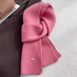 Detail of ribbed knit pink wool scarf with a branded tag on a cozy winter coat