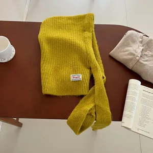 Detailed knit texture of mustard yellow Balaclava with woven brand label on wood table