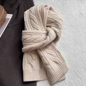 Vue détaillée d'une écharpe en laine à torsades beige avec étiquette WOOL sur le tissu