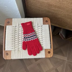 Detail eines roten Fair-Isle-Strickhandschuhs mit geometrischem Muster und Touchscreen-Funktion