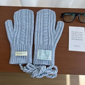 Detail of light blue chunky knit mittens with classic cable pattern and hanging neck cord