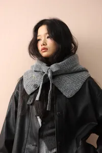 Détail de la cagoule en maille grise avec cordon de serrage et bouton sur veste en cuir